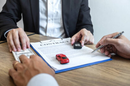 Car rental and Insurance concept, Young salesman receiving money and giving car's key to customer after sign agreement contract with approved good deal for rent or purchase.